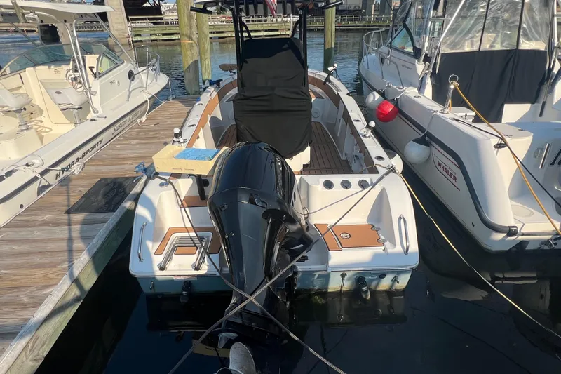 Slide: The Image of 2019 Sea Hunt Ultra 234 boat docked with outboard motor, surrounded by other boats. - 2