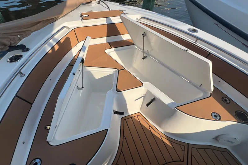 Slide: The Image of 2019 Sea Hunt Ultra 234 boat with open storage compartments and brown deck. - 19