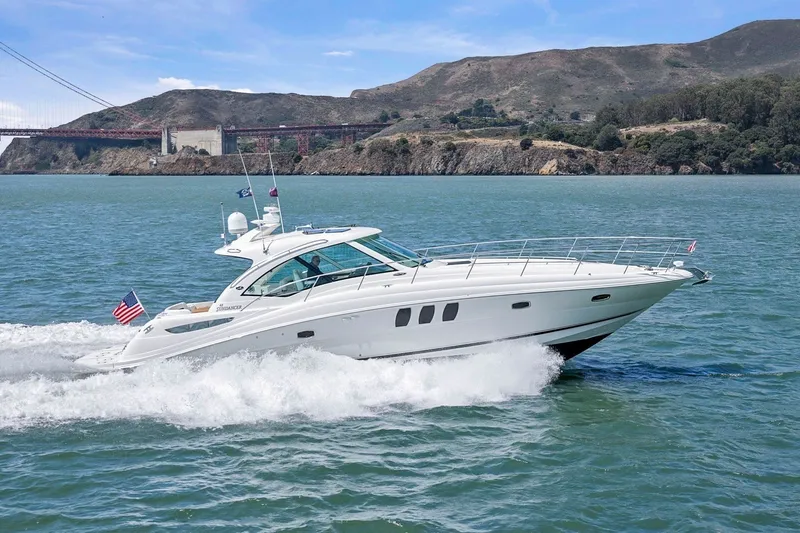 The Image of A 2007 Sea Ray 48 Sundancer cruising swiftly on the water, with a bridge in the background. - 0