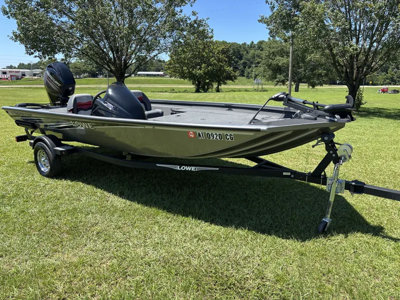 Slide: The Image of A 2018 Lowe Stinger 178 boat on a trailer, set on a grassy field. - 2