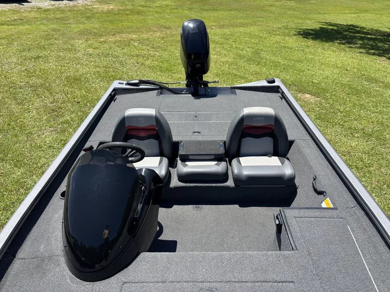 Slide: The Image of The image shows a 2018 Lowe Stinger 178 boat on grass. It features two seats and a helm. - 16