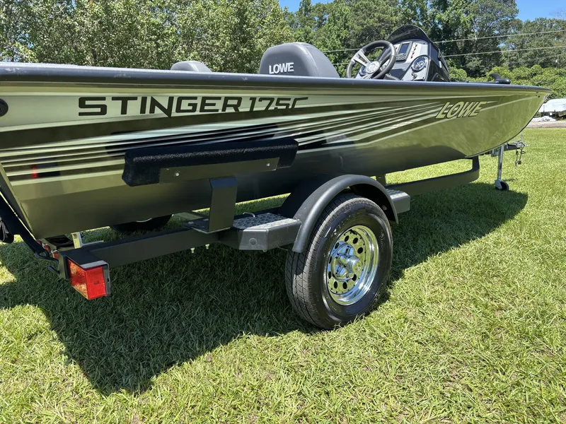 Slide: The Image of A 2018 Lowe Stinger 178 boat on a trailer, set on a grassy field. - 6