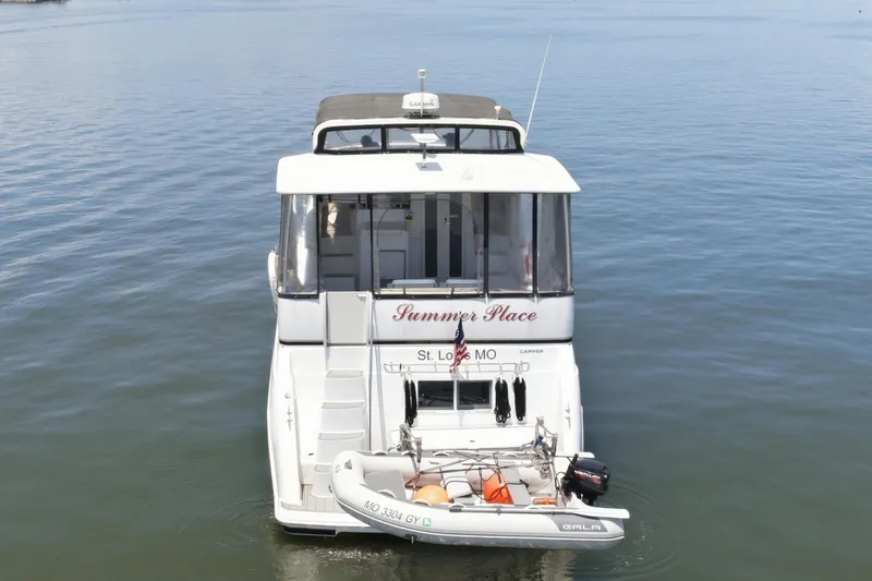 Slide: The Image of A 2000 Carver 406 Aft Cabin Motor Yacht on calm water, featuring a small dinghy. - 2
