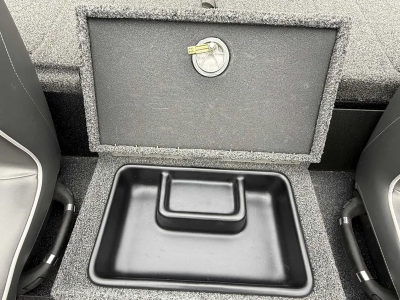 Slide: The Image of An open storage compartment on a boat with gray carpeting and black handles. - 16