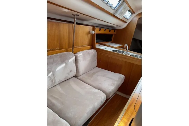 Slide: The Image of Interior of 2000 X-Yachts X-362 Sport, featuring cozy seating and a compact kitchen area. - 12