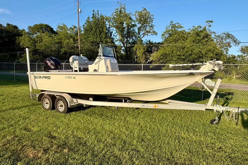 Slide: The Image of 2018 Sea Pro 208 Bay boat on trailer, parked on grass with trees in background. - 4