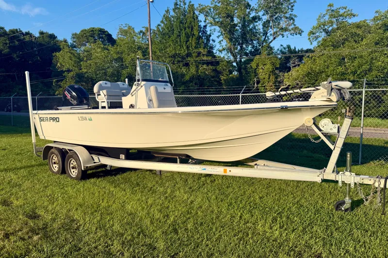 The Image of 2018 Sea Pro 208 Bay boat on trailer, parked on grass with trees in background. - 1