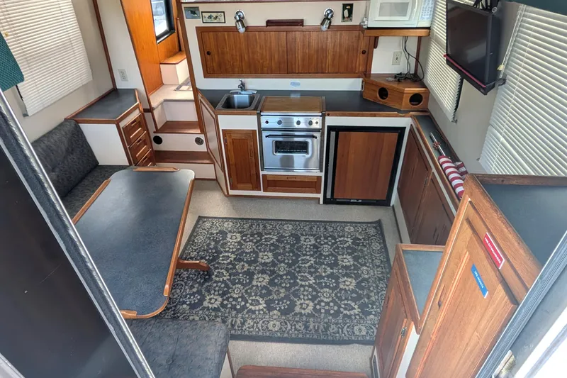 Slide: The Image of Interior of a 1998 Nordic Tug 32, featuring a cozy kitchen and dining area. - 13