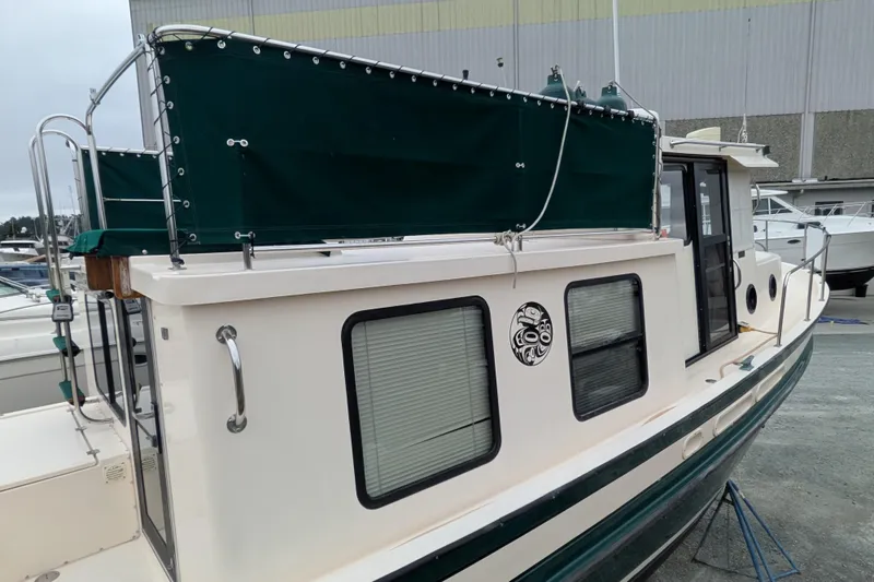 Slide: The Image of 1998 Nordic Tug 32 boat with green canopy and distinctive window design. - 4