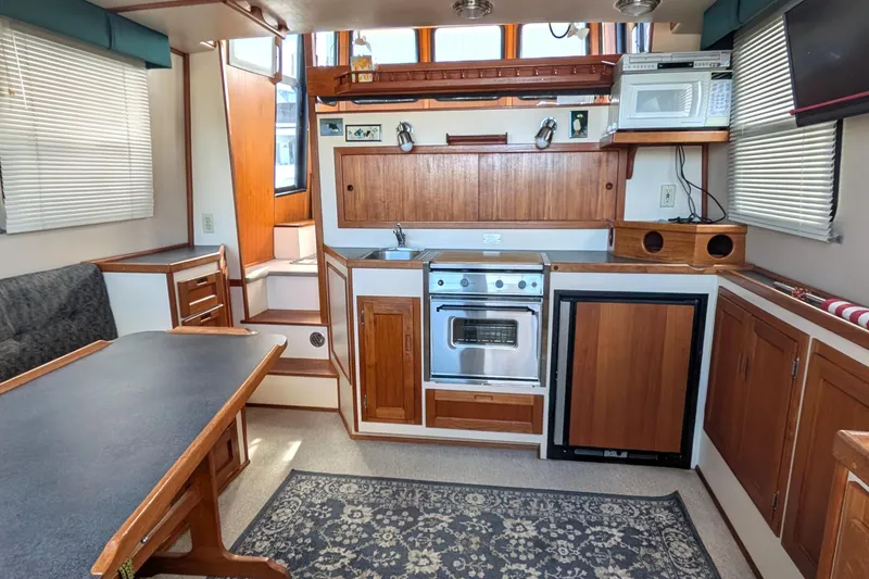 Slide: The Image of Cozy 1998 Nordic Tug 32 interior with kitchen, dining area, and wooden cabinetry. - 17