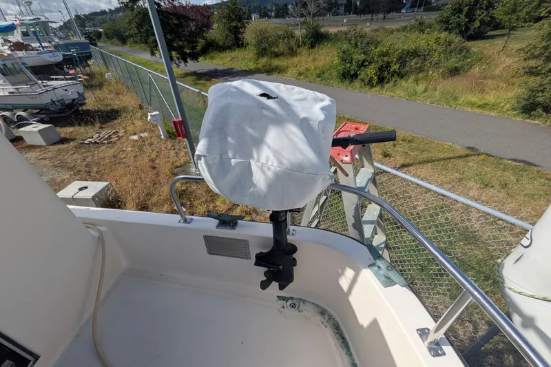 Slide: The Image of Covered outboard motor on a 1998 Nordic Tug 32, docked near a grassy area. - 5
