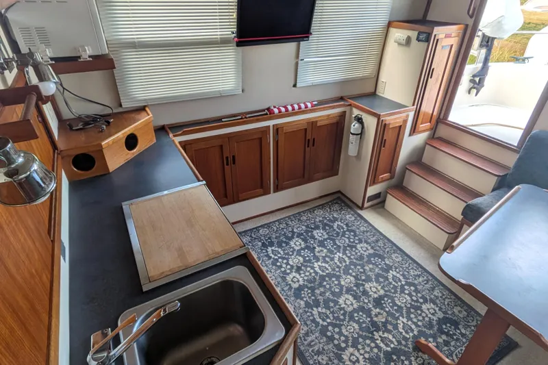 Slide: The Image of Interior of a 1998 Nordic Tug 32, featuring a compact kitchen and cozy seating area. - 19