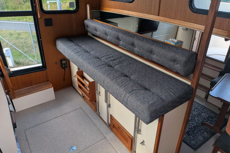 Slide: The Image of Interior of a 1998 Nordic Tug 32, featuring a cushioned bench and wooden cabinetry. - 34