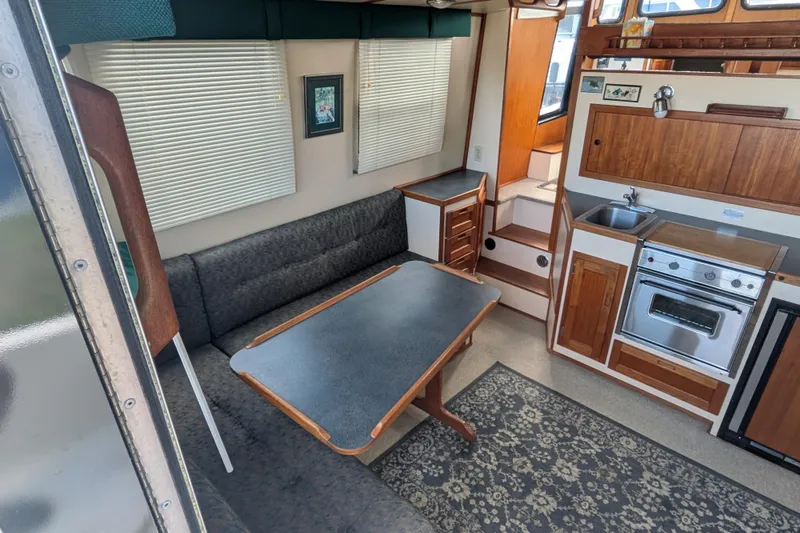 Slide: The Image of Interior of a 1998 Nordic Tug 32, featuring a cozy dining area and compact kitchen. - 15