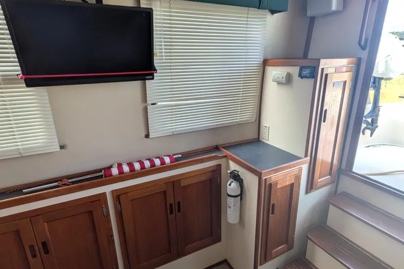 Slide: The Image of Interior of a 1998 Nordic Tug 32 with wooden cabinets, TV, and fire extinguisher. - 21