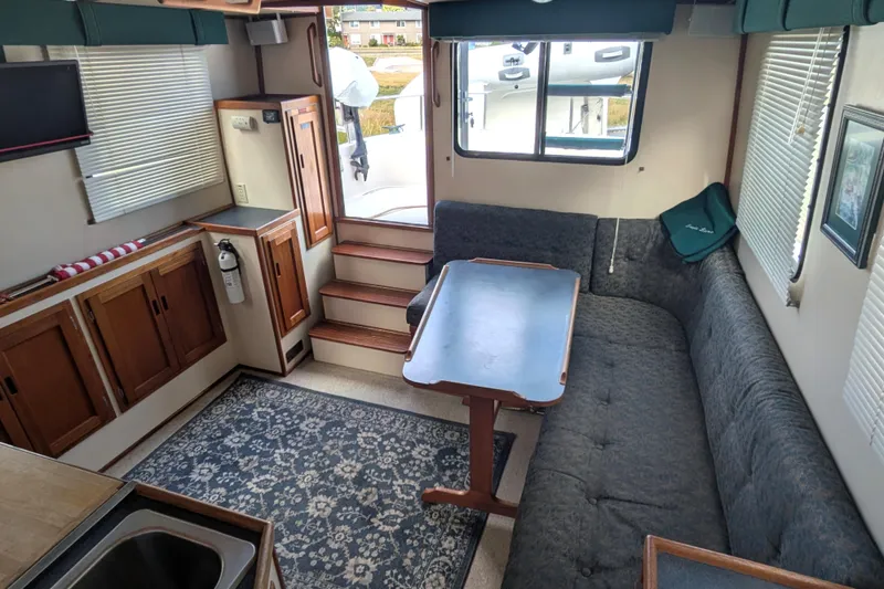 Slide: The Image of Interior of a 1998 Nordic Tug 32, featuring a cozy dining area with a wooden table. - 18