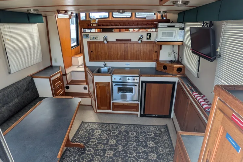 Slide: The Image of Interior of a 1998 Nordic Tug 32, featuring a compact kitchen and dining area. - 14