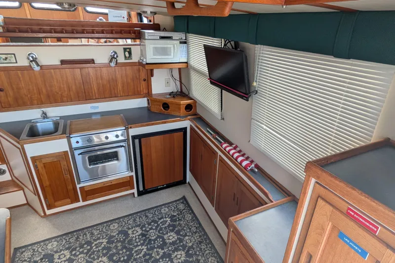 Slide: The Image of Interior of a 1998 Nordic Tug 32, featuring a compact kitchen with wood cabinetry. - 16