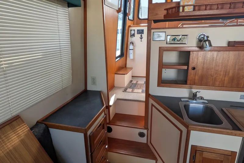 Slide: The Image of Interior of a 1998 Nordic Tug 32, featuring a compact kitchen and wooden cabinetry. - 23