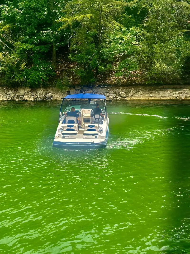 Slide: The Image of A 2016 Chaparral 223 Vortex on a green lake, surrounded by trees. - 5