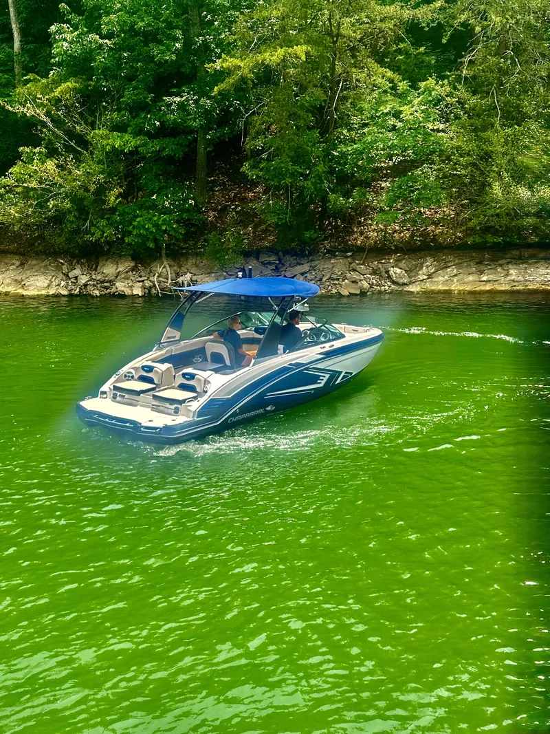 Slide: The Image of A 2016 Chaparral 223 Vortex cruising on a green lake, surrounded by trees. - 4