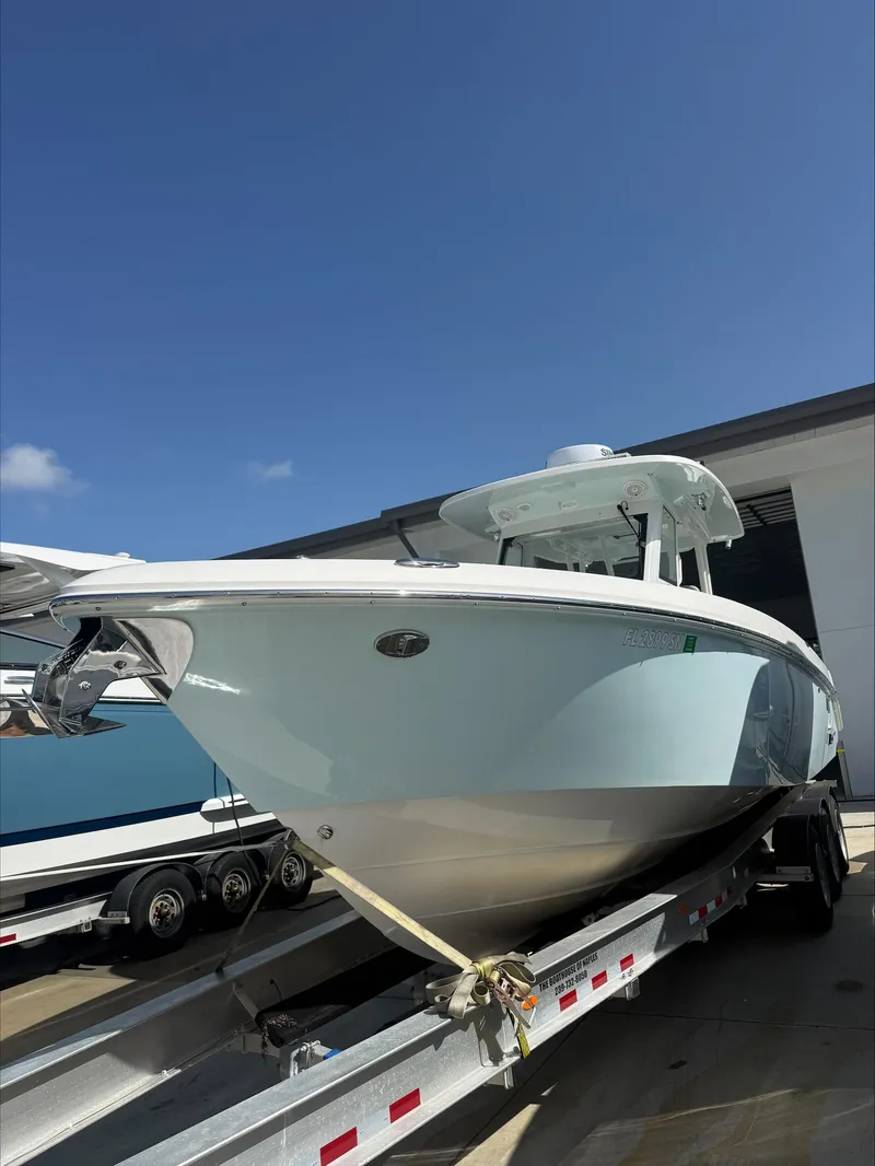 The Image of An Everglades 335 Center Console boat from 2020 on a trailer in front of a building. - 1
