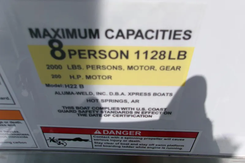 Slide: The Image of 2027 Xpress H22B Bay boat capacity label: 8 persons, 1128 lbs, 200 HP motor. - 2
