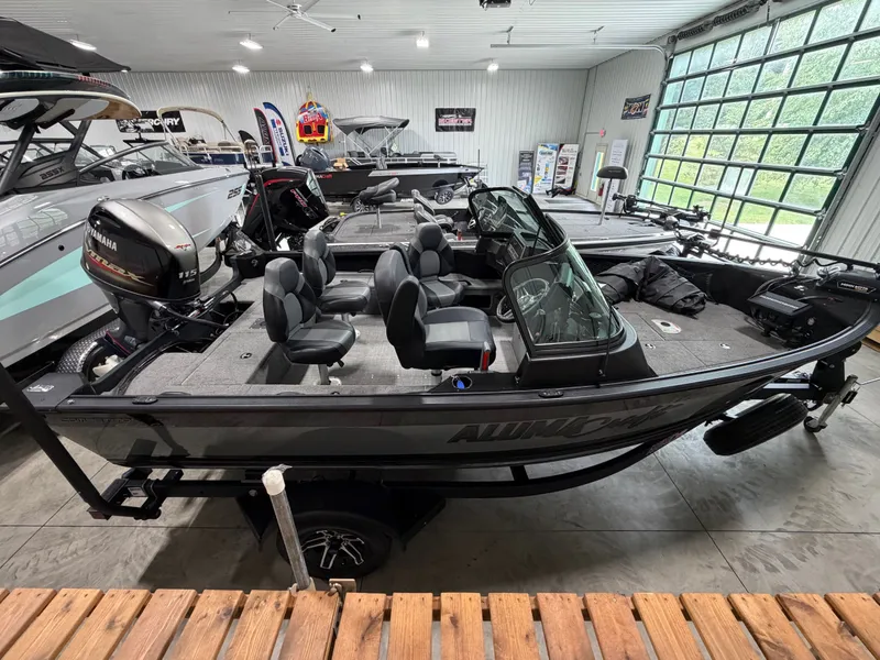 Slide: The Image of A 2023 Alumacraft Competitor Shadow 175 Sport in a showroom. It features multiple seats and an outboard motor. - 5