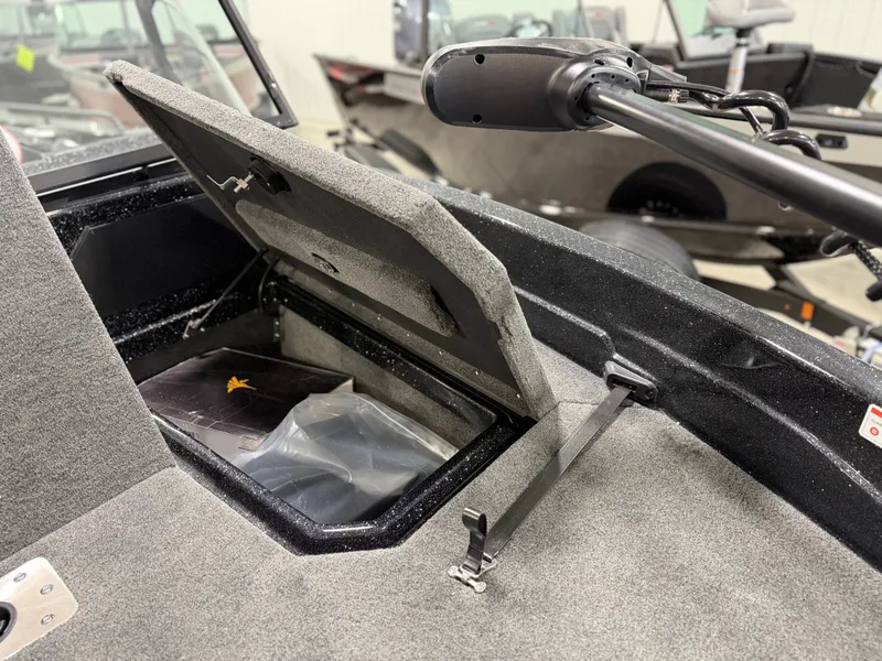 Slide: The Image of An open storage compartment on a 2026 Skeeter WXR1910F boat, featuring gray carpeting. - 17