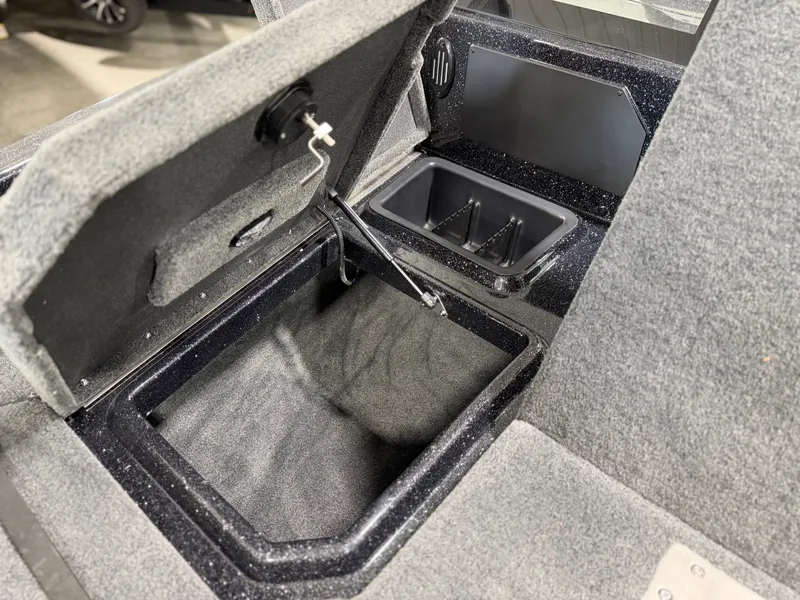 Slide: The Image of An open storage compartment on a boat with gray carpeting. - 16