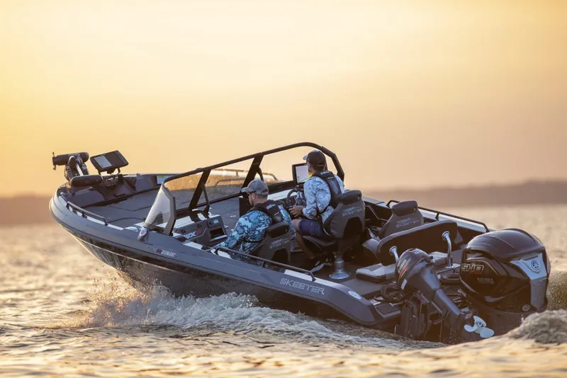 Slide: The Image of Two people ride a Skeeter WXR2060 boat on the water at sunset. - 49