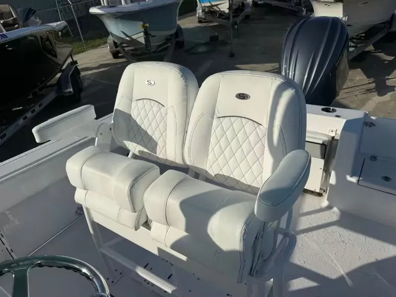 Slide: The Image of Two cushioned seats with armrests on a boat, surrounded by other boats outdoors. - 9