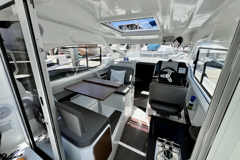 Slide: The Image of Interior of 2023 Beneteau Antares 8 boat, featuring seating, table, and navigation equipment. - 44