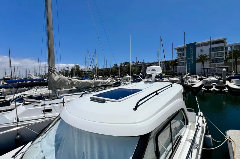 Slide: The Image of 2023 Beneteau Antares 8 docked at marina, surrounded by sailboats and modern buildings. - 24