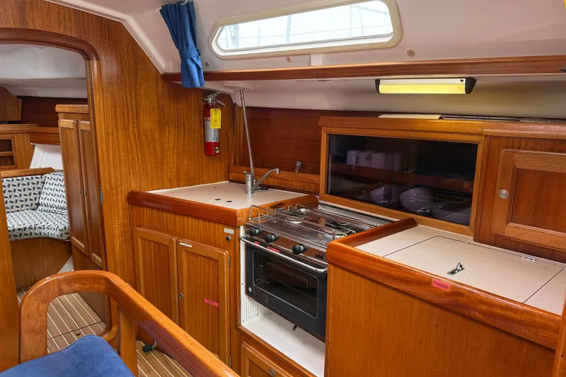 Slide: The Image of Interior of 2001 Dufour 36 Classic yacht, featuring a wooden galley with stove and storage. - 9