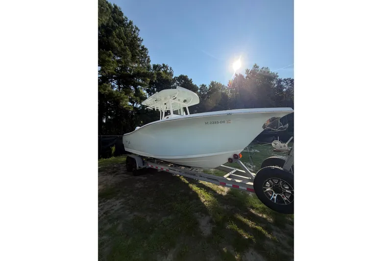 The Image of 2020 Sea Pro 259 Center Console boat on trailer, surrounded by trees and sunlight. - 1