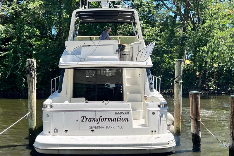 Slide: The Image of 2003 Carver 450 Voyager Pilothouse yacht docked, named "Transformation," in a serene wooded area. - 4