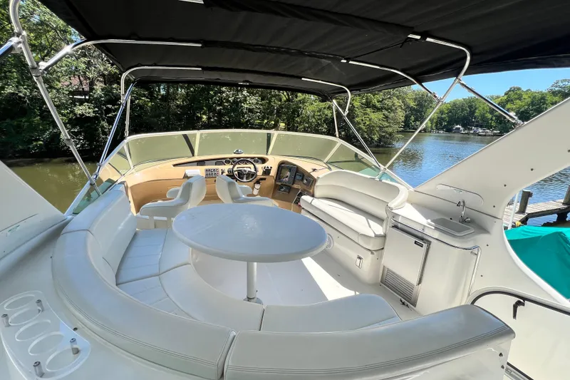 Slide: The Image of 2003 Carver 450 Voyager Pilothouse interior with seating, table, and helm, docked by a scenic river. - 40