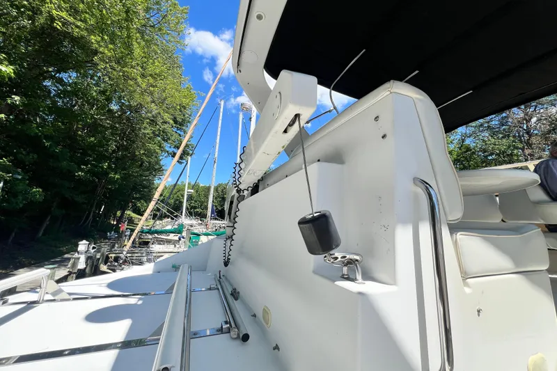 Slide: The Image of 2003 Carver 450 Voyager Pilothouse yacht docked, featuring sleek white design and lush green surroundings. - 46