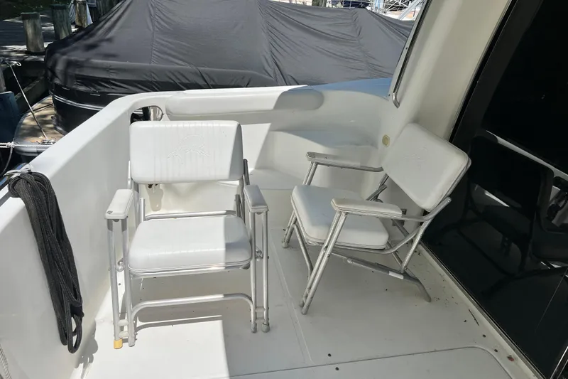 Slide: The Image of 2003 Carver 450 Voyager Pilothouse deck with two white chairs. - 55