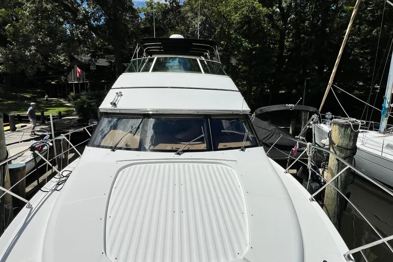 Slide: The Image of 2003 Carver 450 Voyager Pilothouse yacht docked in a marina surrounded by trees. - 59