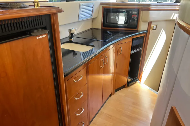 Slide: The Image of Luxurious 2003 Carver 450 Voyager Pilothouse kitchen with wood cabinetry and modern appliances. - 25