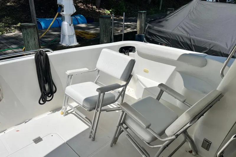 Slide: The Image of 2003 Carver 450 Voyager Pilothouse deck with white chairs and dock view. - 54