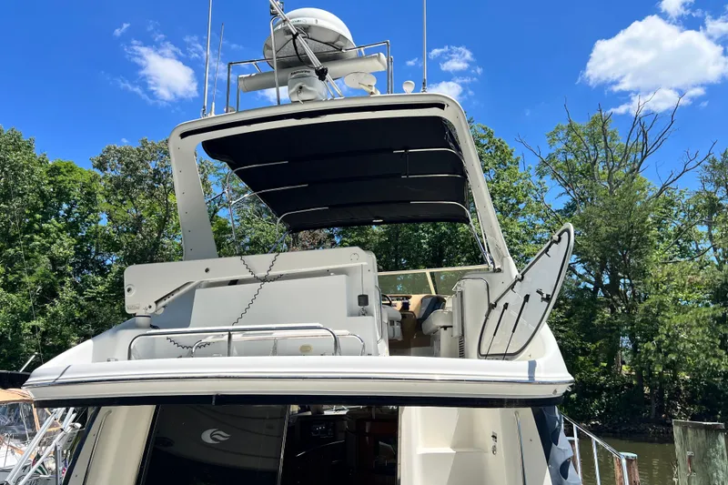 Slide: The Image of 2003 Carver 450 Voyager Pilothouse yacht with open deck, surrounded by trees and blue sky. - 45