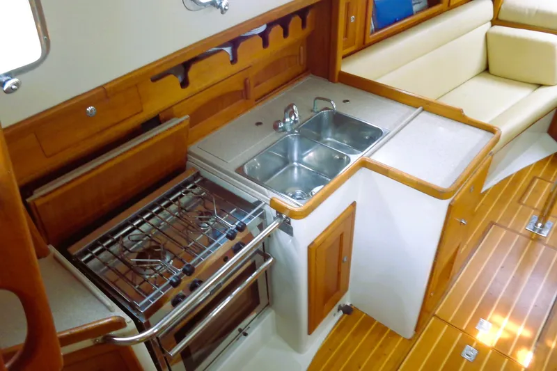 Slide: The Image of Galley kitchen in 2008 Pacific Seacraft 31 sailboat with stove, sink, and wooden cabinetry. - 4