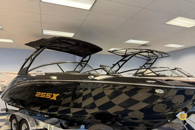 The Image of 2026 Yamaha Boats 255XD in showroom, sleek black design with checkered pattern. - 0