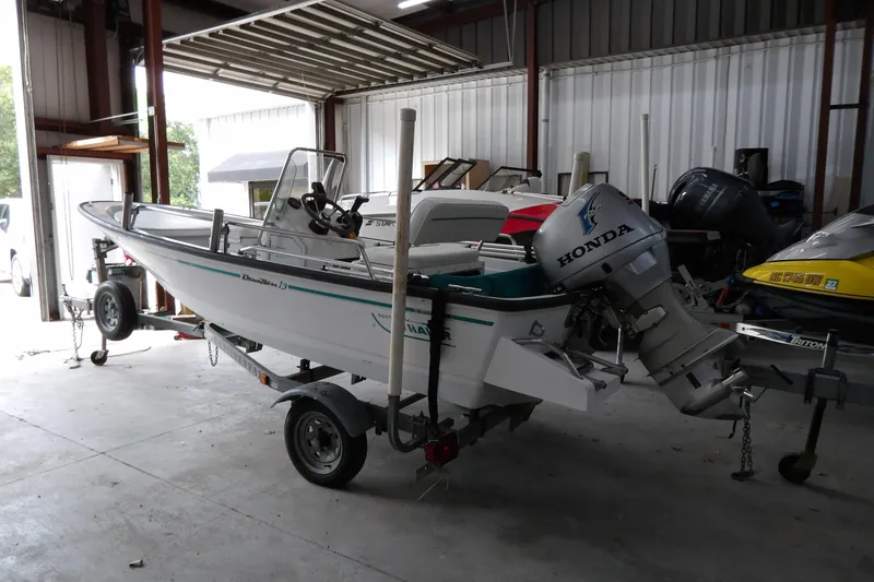 The Image of 1997 Boston Whaler Dauntless 13 boat with Honda outboard motor in a garage. - 1