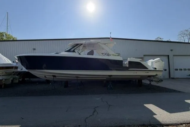 Slide: The Image of 2022 Tiara Yachts 43 LS boat on display outside a warehouse under bright sunlight. - 1