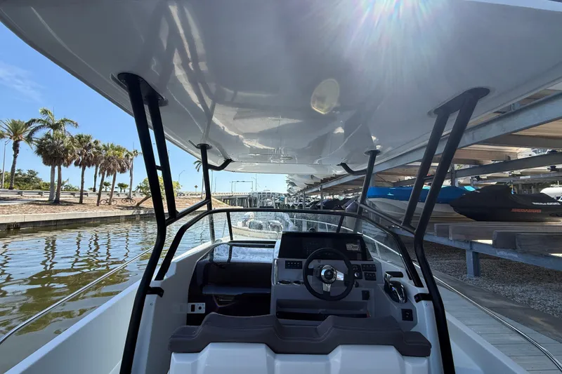 Slide: The Image of 2020 Jeanneau Leader 7.5 CC boat interior with steering wheel, docked near palm trees. - 26