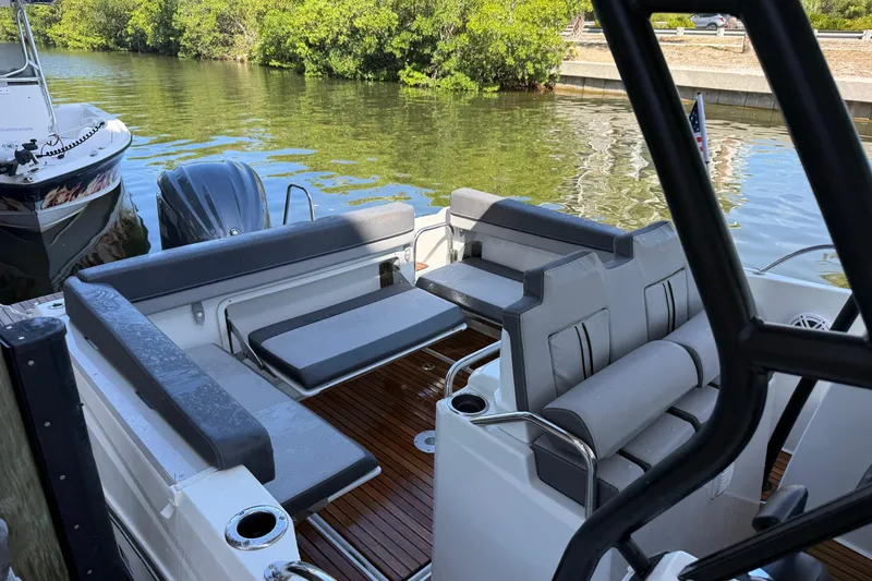Slide: The Image of 2020 Jeanneau Leader 7.5 CC boat interior with seating, docked by lush greenery. - 5